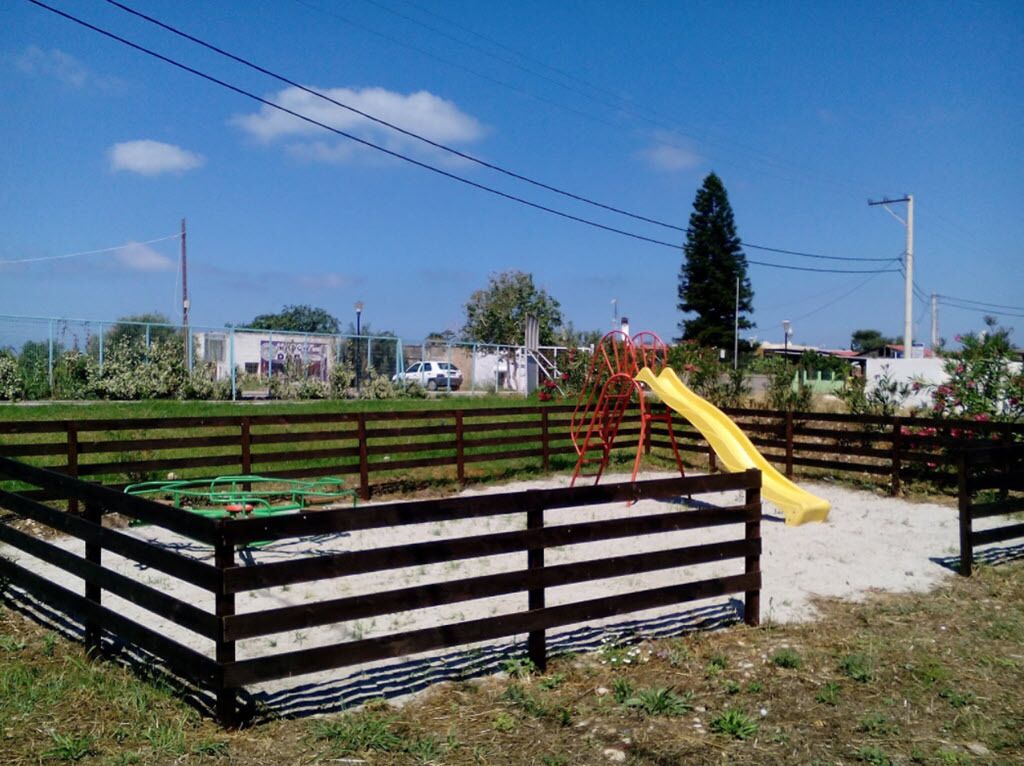 A fenced playground with a yellow slide and climbing structure.