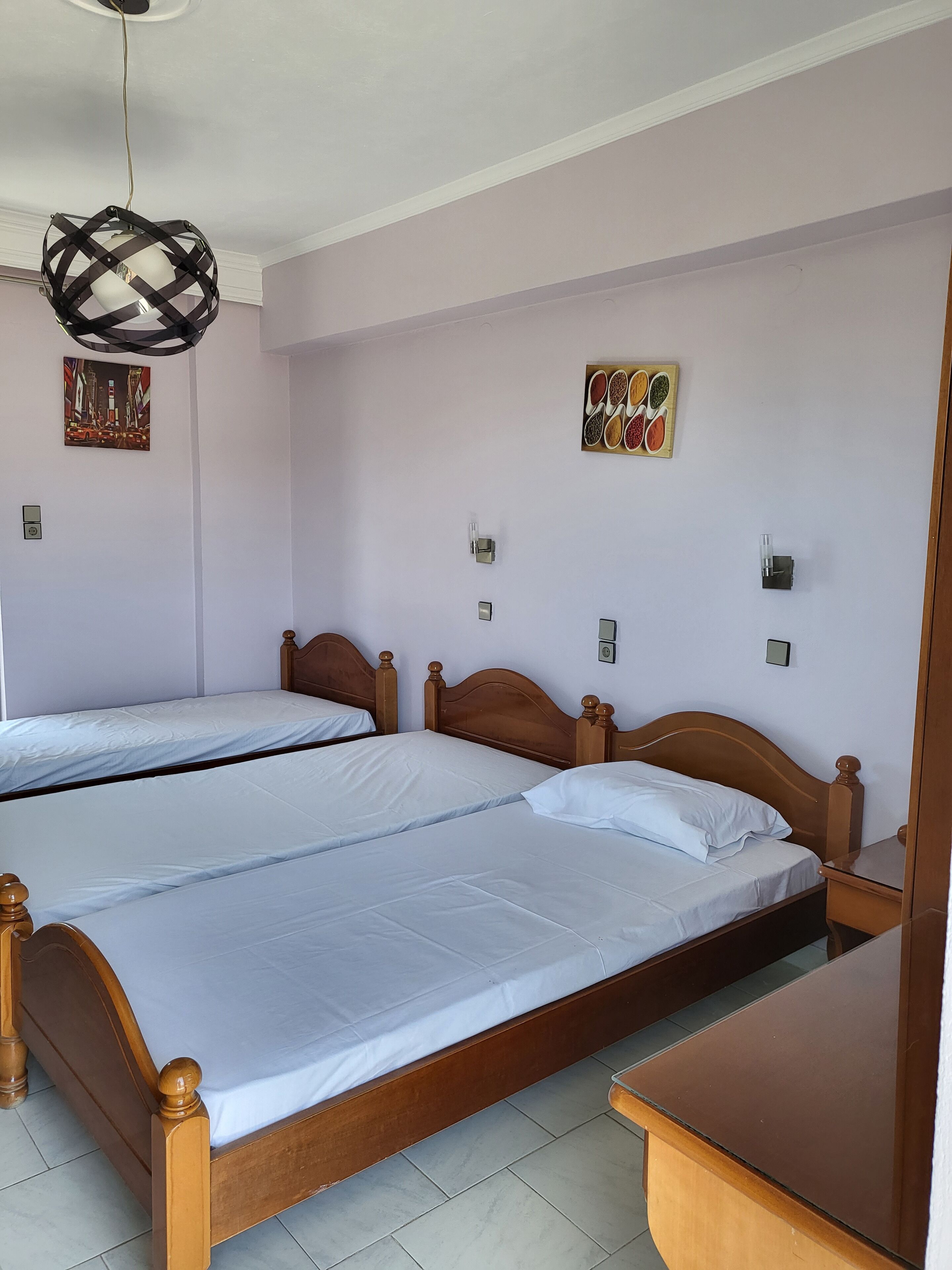 Ein Hotelzimmer mit zwei Holzbetten, einer hängenden Leuchte und Wandleuchten.