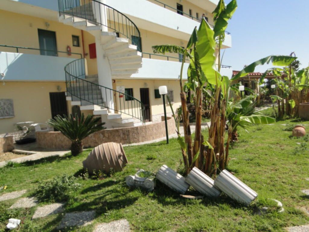 Un edificio a più piani con una scala a chiocciola, un giardino con piante di banano e un cielo sereno.