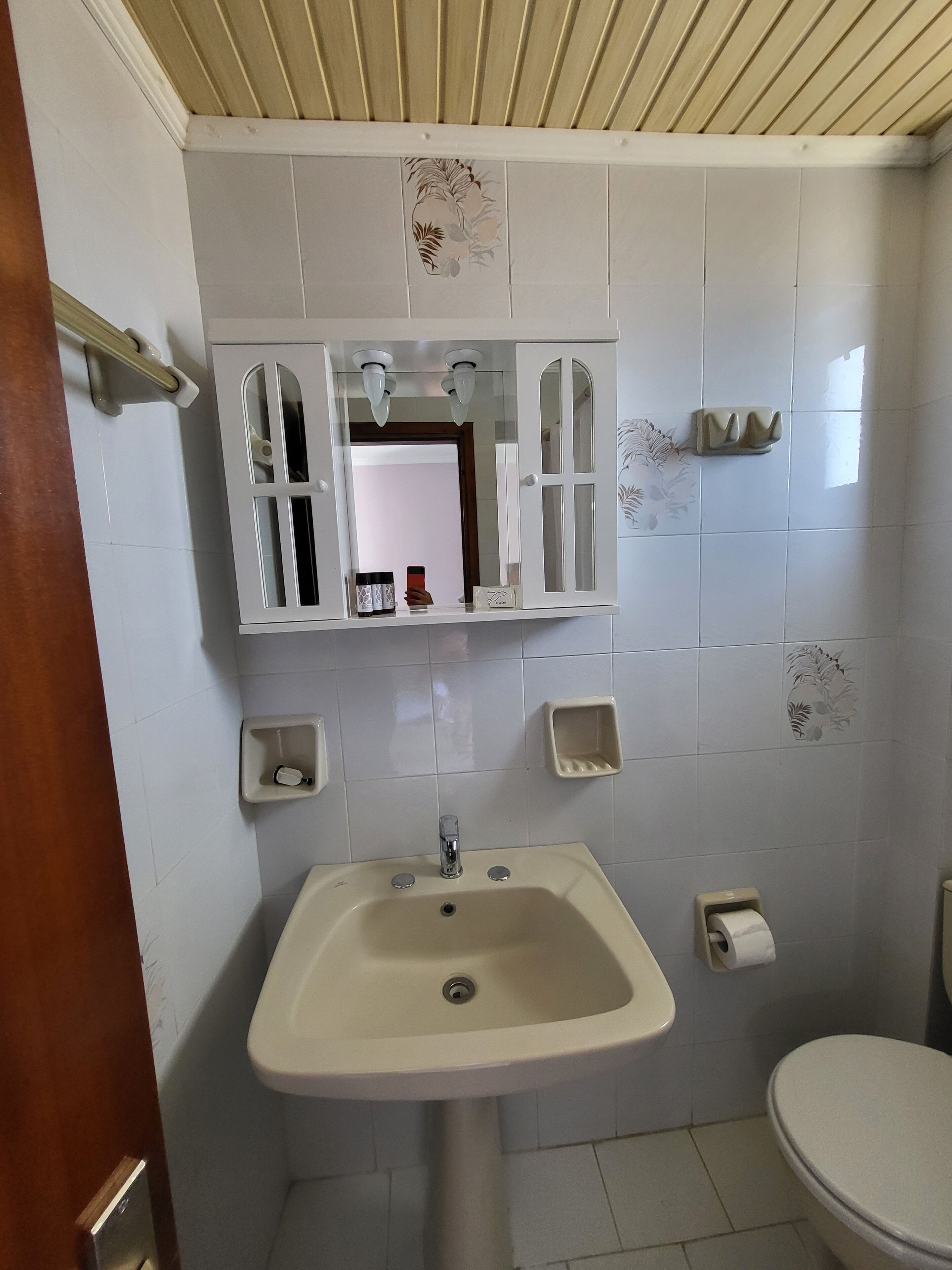 A bathroom with a sink, mirror, toilet, and a towel rack.