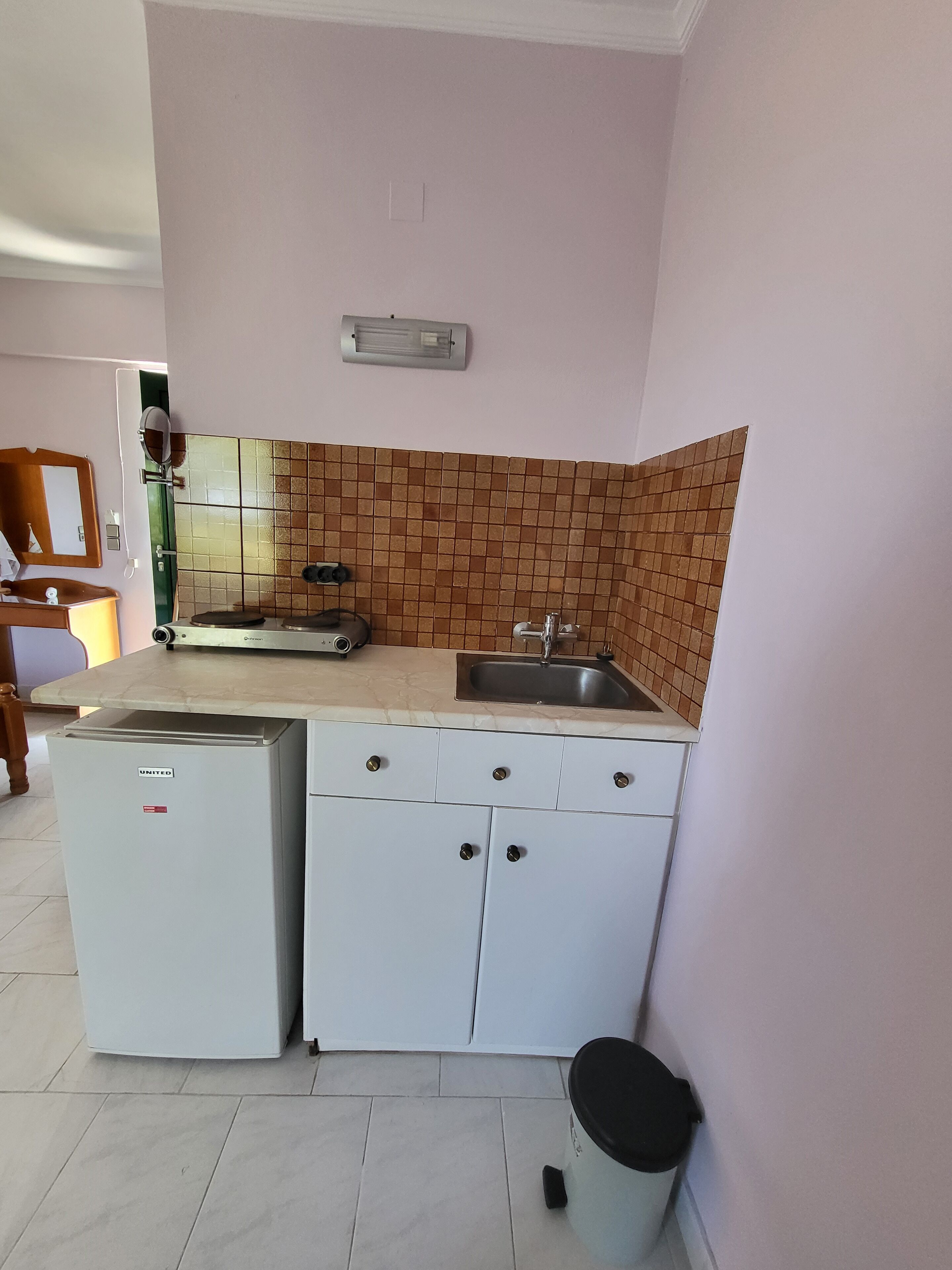 A compact kitchen with a refrigerator, sink, and cabinets.