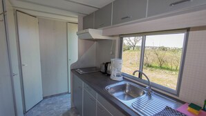 A compact kitchen with a built-in sink, a window with a view of the outdoors, and a coffee maker on the counter. - Island of Rügen by the lake, only 10 minutes from the Baltic seaside resort of Binz (Zirkow)