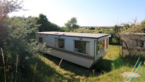 A mobile home with a flat roof, large windows, and a sliding door. - Island of Rügen by the lake, only 10 minutes from the Baltic seaside resort of Binz (Zirkow)