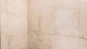 A shower area with beige tiles and a mosaic border.
