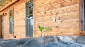 Una cabaña de madera con un jacuzzi y dos bebidas verdes en la pared.