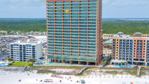 Een hoog hotel met meerdere verdiepingen, een zwembad en uitzicht op het strand.