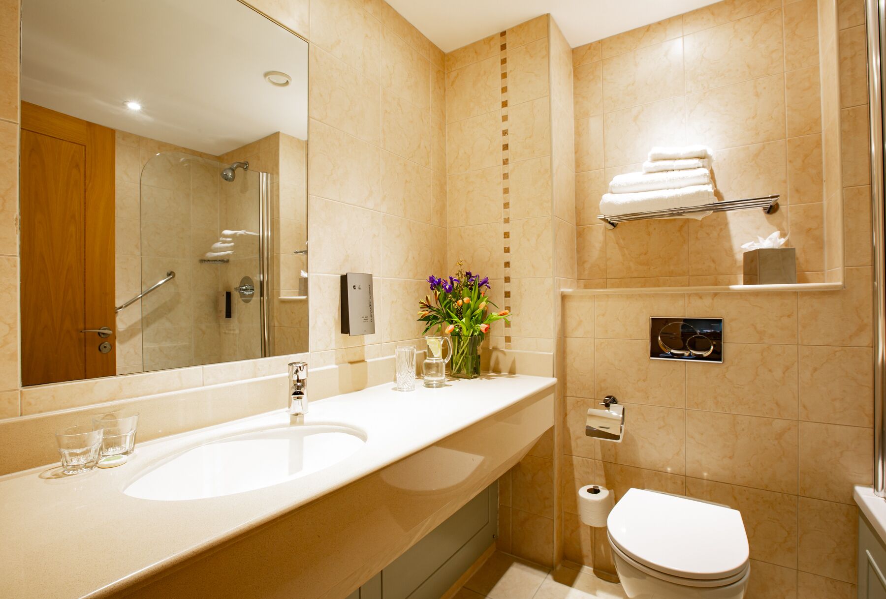 A modern bathroom with a large sink, a glass shower enclosure, a toilet, and a towel rack.