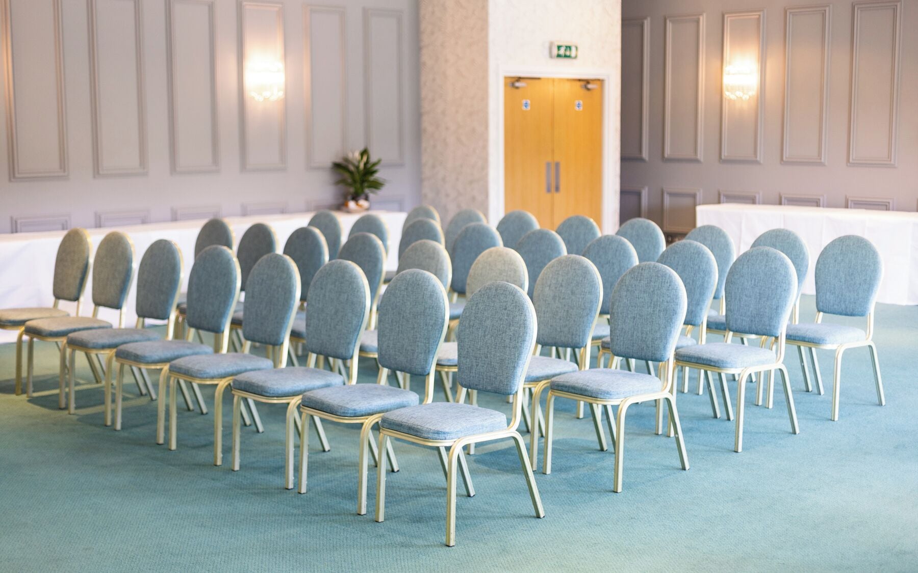 Ett konferensrum med rader av stolar, ett bord och en dörr.