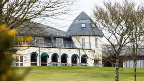A large building with a prominent tower, multiple arched windows, and a balcony with chairs. - Lanhydrock Hotel and Golf Club (Bodmin)