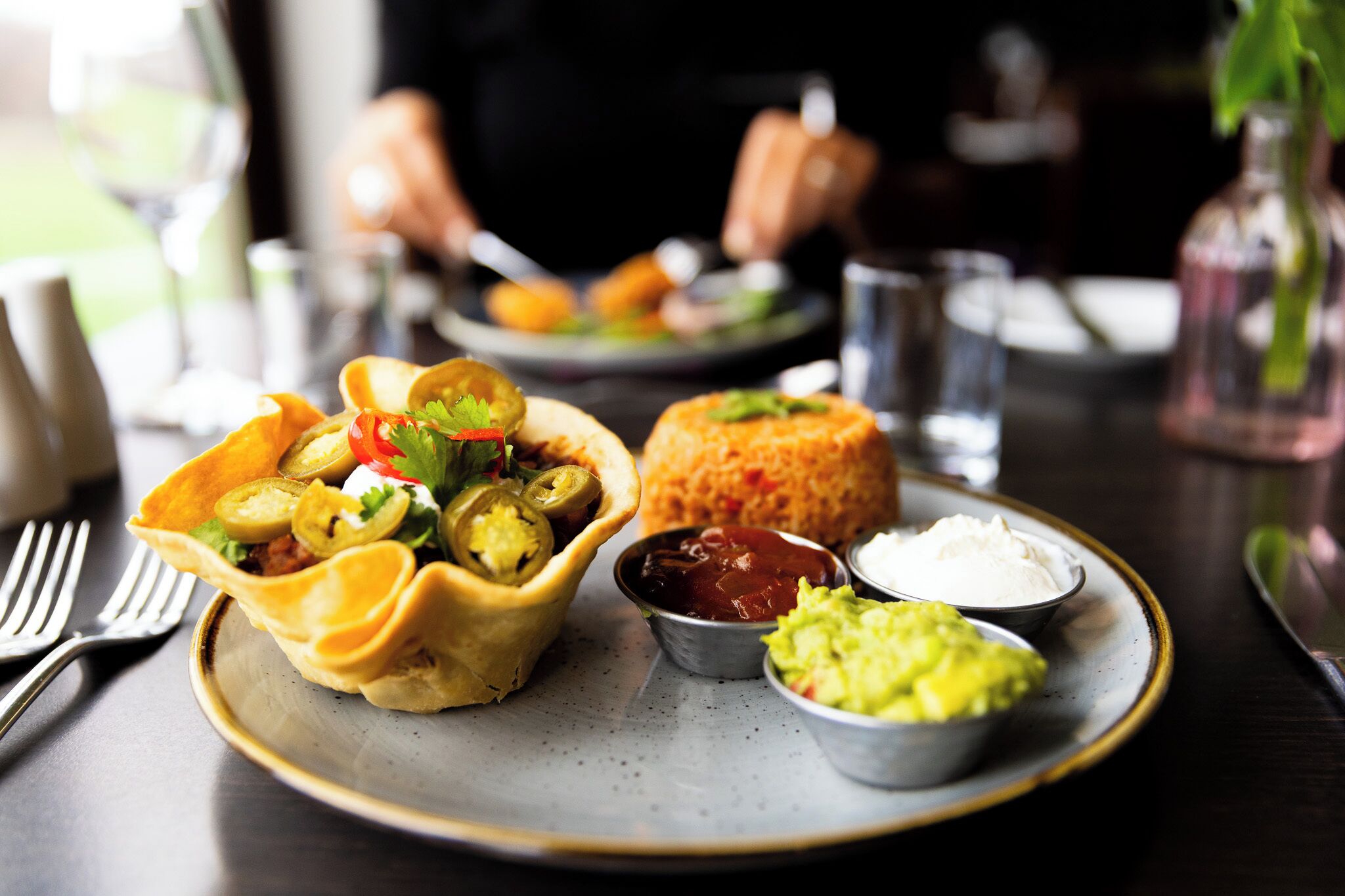 A plate with a taco, rice, guacamole, and salsa.