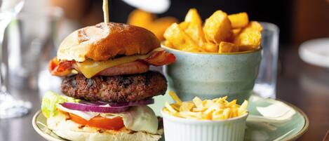 A plate with a burger, fries, and a small bowl of sauce.