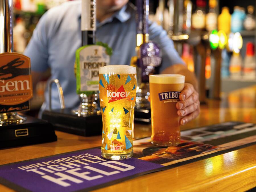 A bar with two glasses of beer, a tap labeled 'Gem,' and a coaster with 'Independence Tight Held' text.