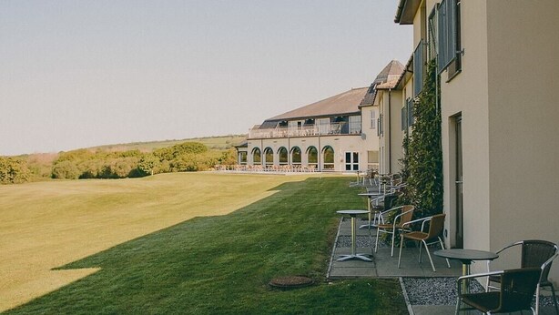 A building with a patio area featuring outdoor seating and a well-maintained lawn. - Lanhydrock Hotel and Golf Club (Bodmin)