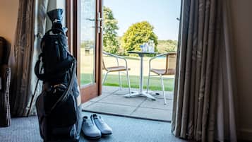A room with a view of a garden, a door with a pair of shoes, and a black bag.