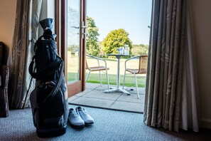 A room with a view of a garden, a door with a pair of shoes, and a black bag.