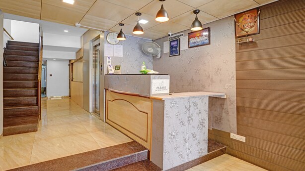 A hotel reception area with a marble counter, a clock, a fan, and a staircase. - Itsy Hotels Aakash,100 Mts From Sardar Patel Stadium (Ahmedabad)