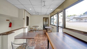 A restaurant interior with a long wooden table, metal chairs, and a fire extinguisher on the wall. - Itsy Hotels Aakash,100 Mts From Sardar Patel Stadium (Ahmedabad)