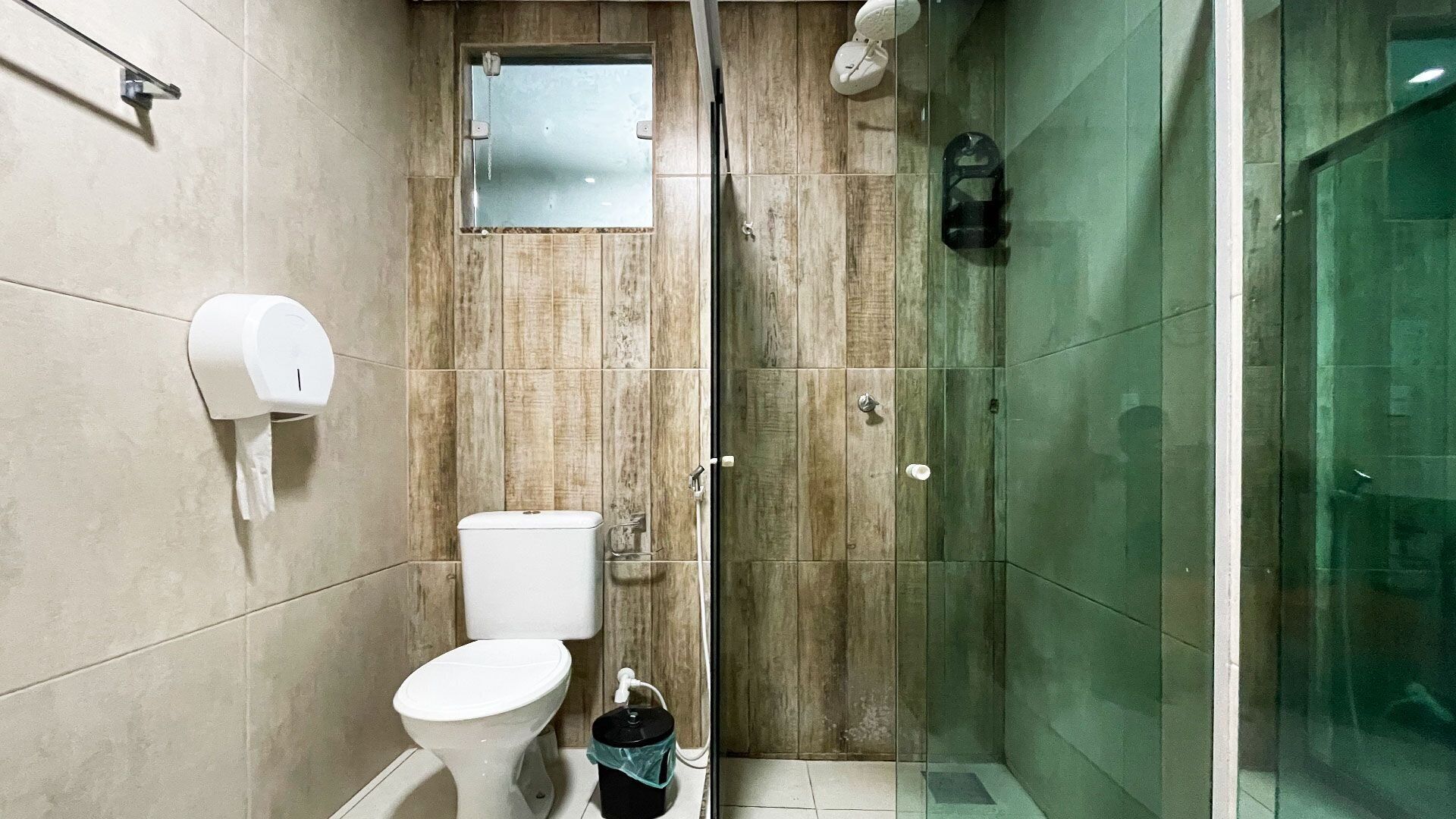 A small, compact bathroom with a toilet, a bidet, and a glass-enclosed shower area.