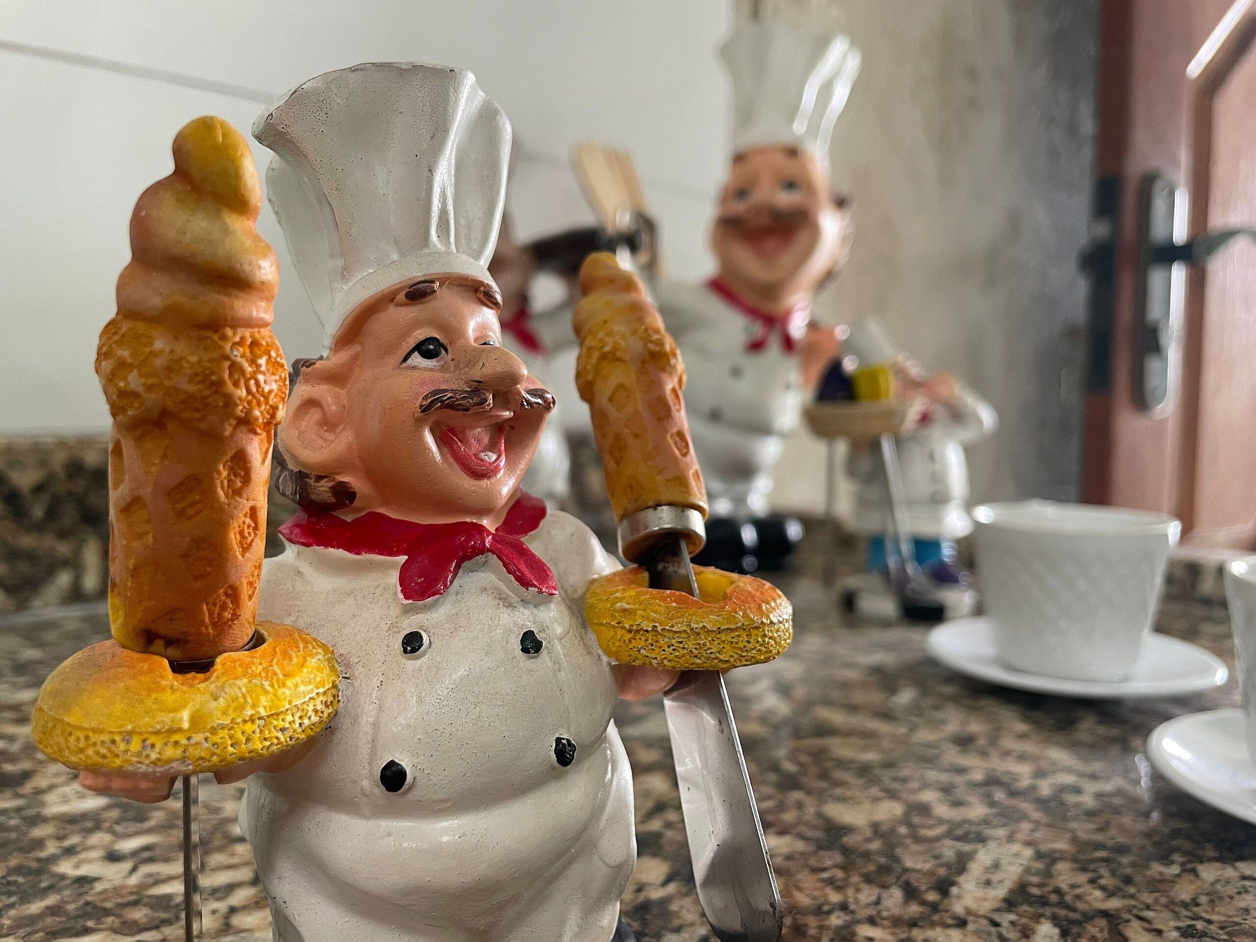 Eine Küchenzeile mit Keramik-Kochfiguren, die Spieße mit Speisen halten.