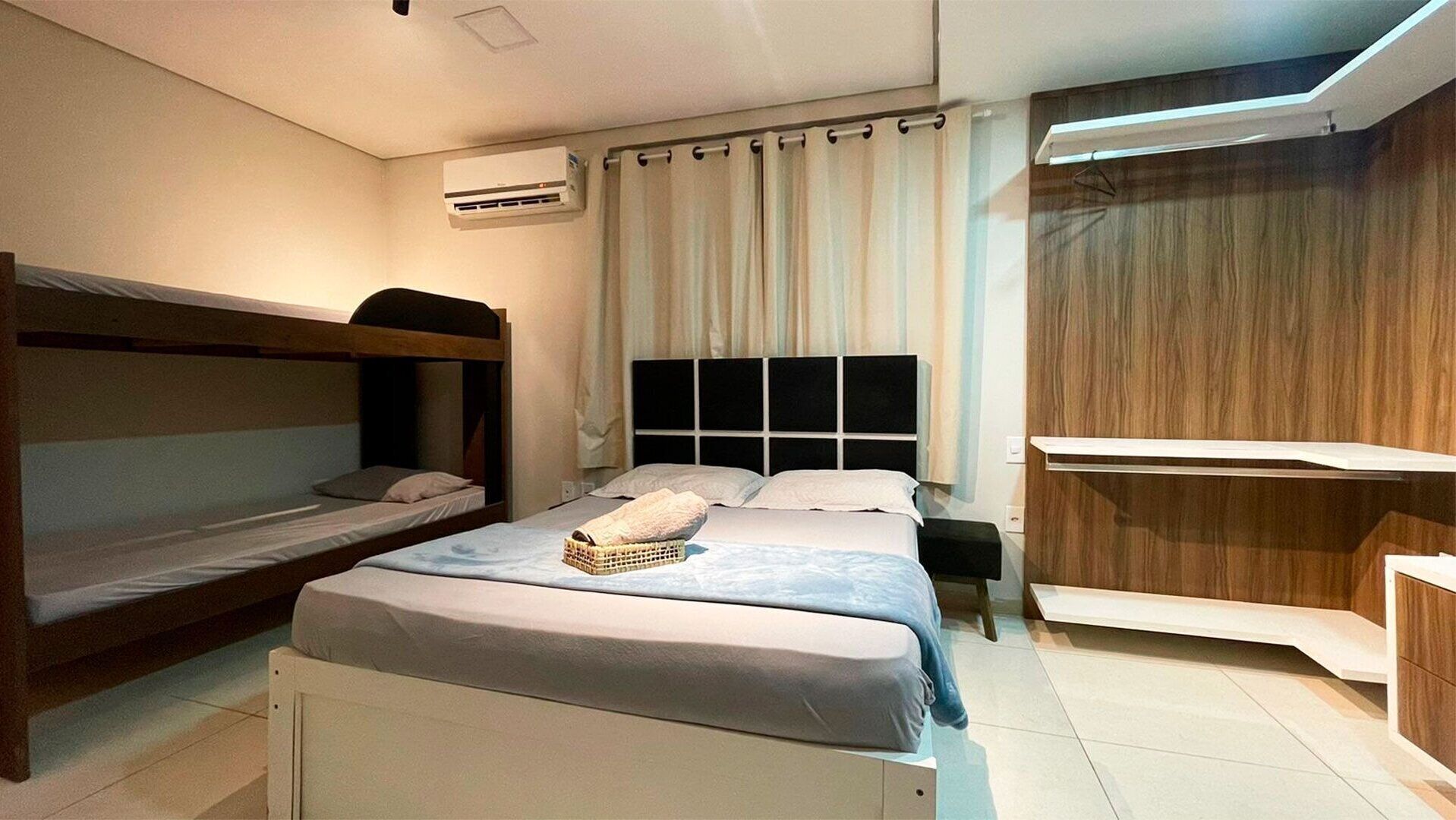 A modern bedroom with bunk beds, a wooden wardrobe, and a built-in desk.