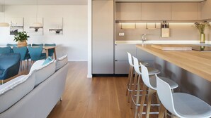A modern kitchen with a wooden countertop, white bar stools, and a built-in oven. - Nautiko by FeelFree Rentals (Donostia)