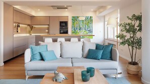 A modern living room with a grey sofa, teal cushions, a wooden coffee table, and a small turtle sculpture. - Nautiko by FeelFree Rentals (Donostia)