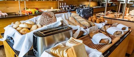 A buffet with various breads, pastries, and a toaster.