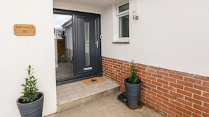 A house entrance with a dark-colored door, a small window, and a sign reading "THE DINGLE".