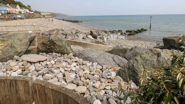 A rocky beach with a wooden walkway and a view of the sea.