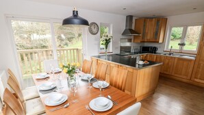 A modern kitchen with wooden cabinets, a central island, and a dining area with a wooden table set for six.