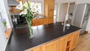 A modern kitchen with wooden cabinets, a black countertop, and a stainless steel refrigerator.