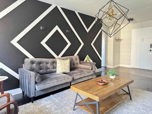 Relax in this stylish living room with a geometric wall design, a comfortable sofa, and a coffee table.