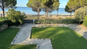 Ein angelegter Garten mit Kiesweg, ordentlich geschnittenen Hecken und Blick auf das Meer.