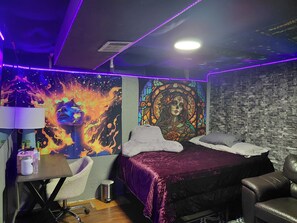 A room with a bed, a desk, a chair, a trash bin, and a wall with a mural.
