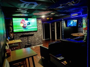 A bar area with a flat-screen TV, wooden tables, and a seating area with a couch.