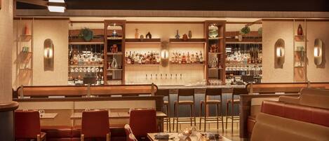 Un restaurante con cabinas, mesas y una zona de bar con estantes llenos de botellas y vasos.