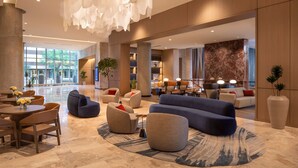 Un vestíbulo espacioso con muebles modernos, un gran candelabro y un mostrador de recepción de mármol.