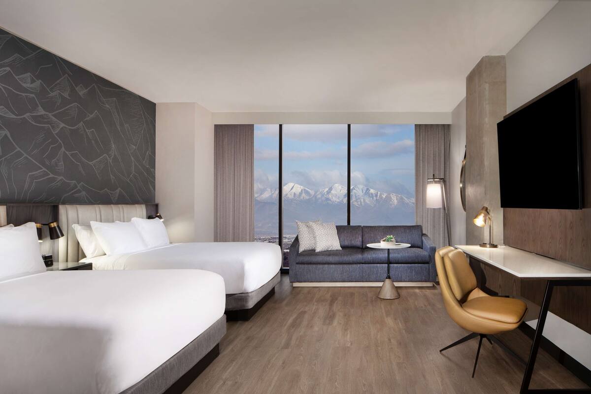 Une chambre d’hôtel avec deux lits, un canapé, un bureau et une chaise.
