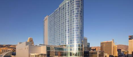 A modern hotel with a curved glass facade, a prominent entrance, and a parking area in front.