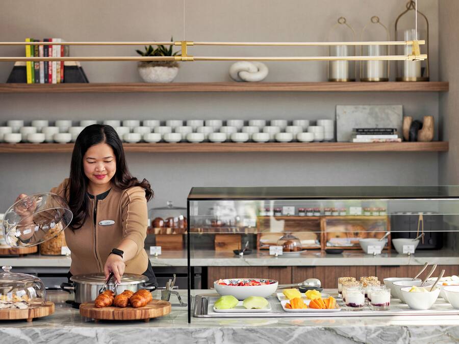 A buffet setup with various food items and a person serving.