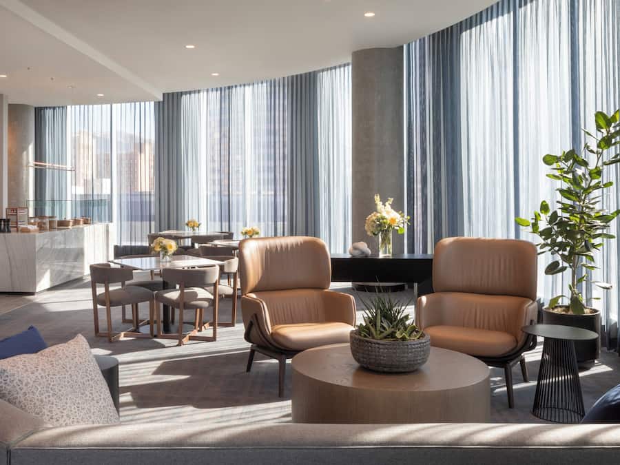 A modern living room with a sofa, two armchairs, a coffee table, and a dining area with a table and chairs.
