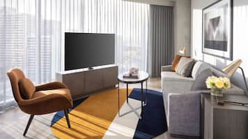 Un soggiorno moderno con un'ampia televisione a schermo piatto, un divano, un tavolino e una poltrona.