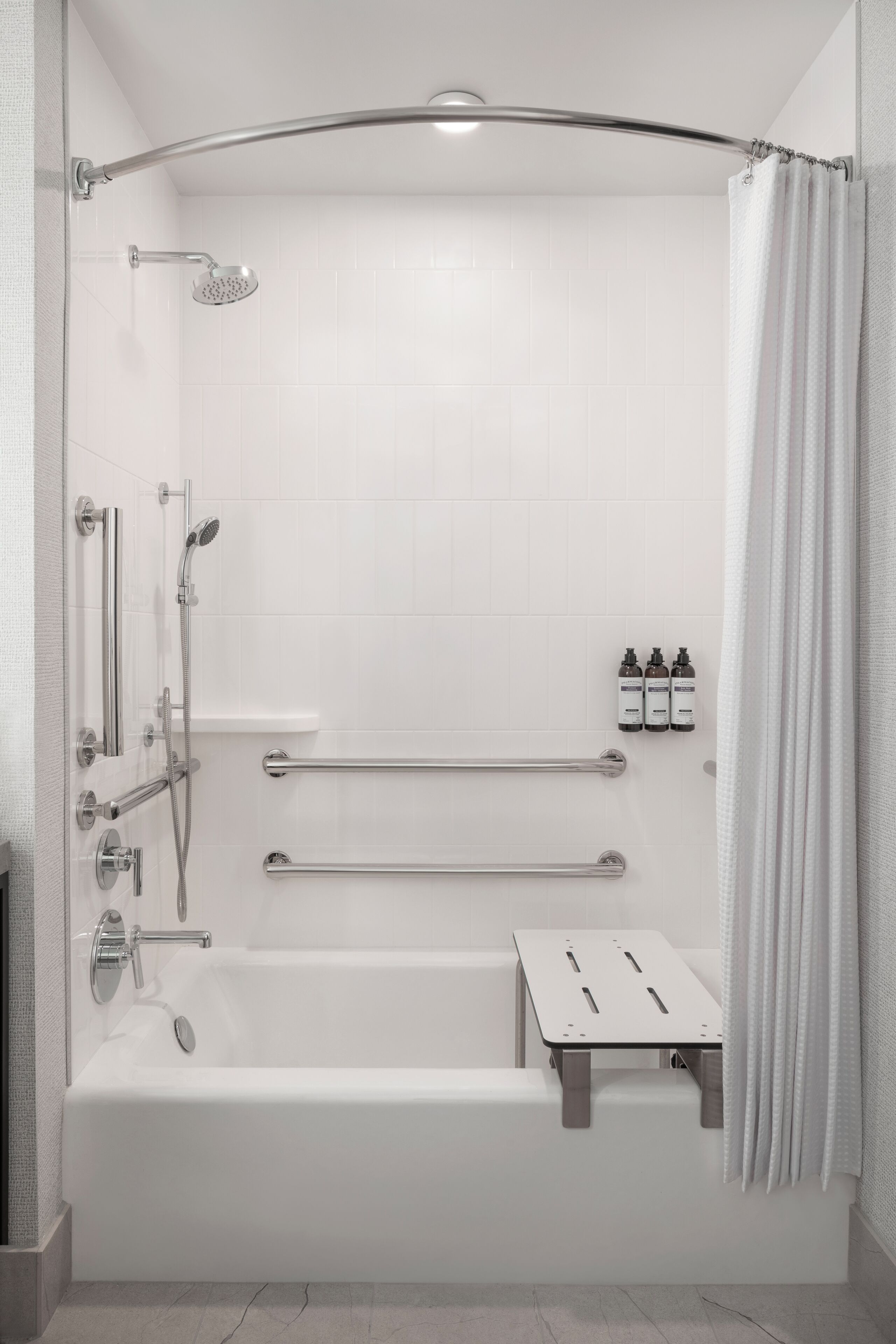 A modern bathroom with a bathtub, shower, and grab bars.
