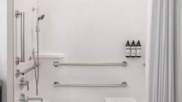 A modern bathroom with a bathtub, shower, and grab bars.