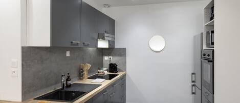 Eine moderne Küche mit grauen Schränken, einem schwarzen Spülbecken und einem eingebauten Backofen.