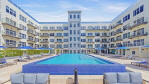Een modern hotel met een centraal gelegen zwembad, omringd door loungegedeeltes en meerdere balkons.