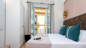 Una habitación de hotel con una cama, un banco y vistas a un balcón.