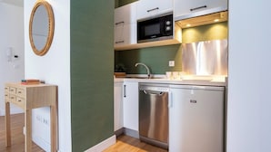 Cocina compacta con alacenas blancas, un microondas Bosch, lavavajillas y una mesita de madera con espejo.