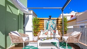 A patio with wicker furniture, a white table, and a wooden fence. - Genteel Home Mercado Central Terrace (Cadiz)