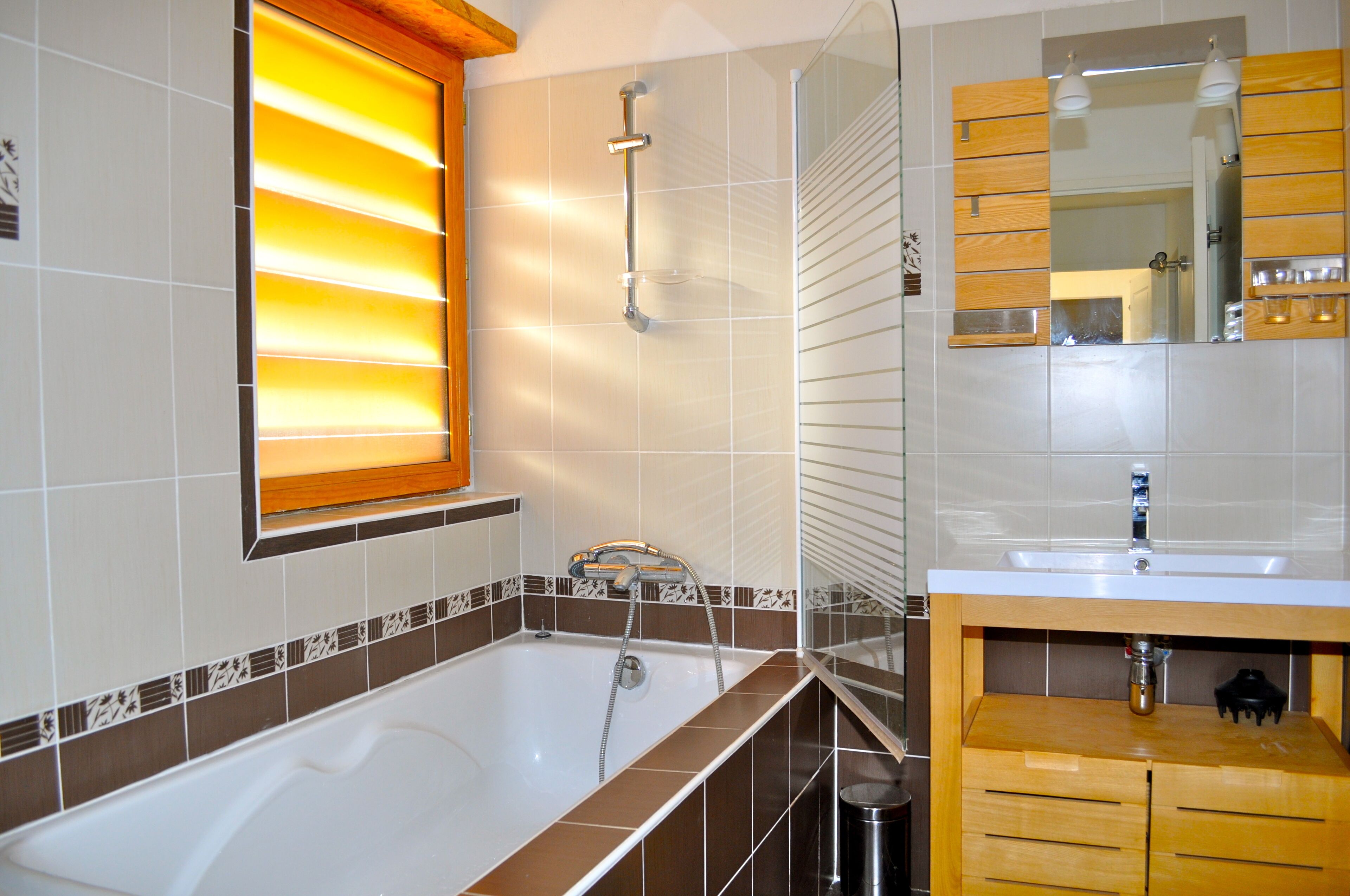 Un bagno moderno con vasca, un mobile toilette con specchio e una finestra con persiane.